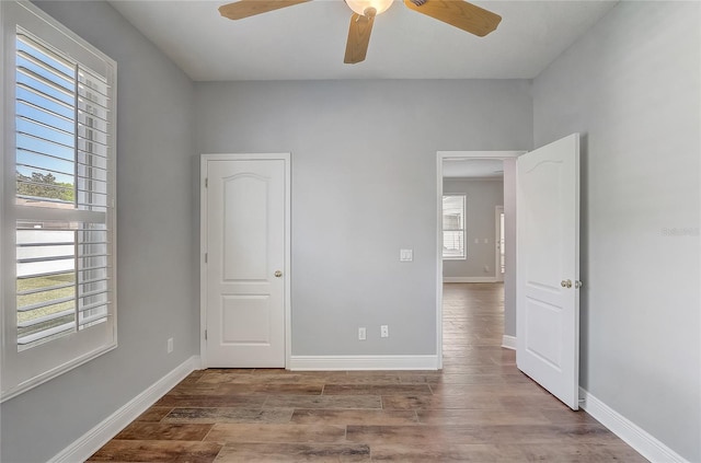 unfurnished bedroom with a ceiling fan, wood finished floors, and baseboards