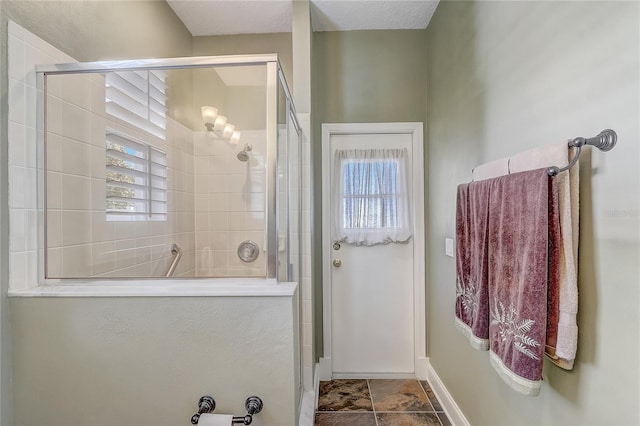 bathroom featuring a shower stall and baseboards