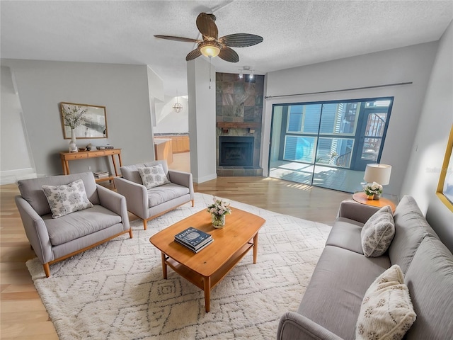 living room with a fireplace, a textured ceiling, baseboards, and wood finished floors