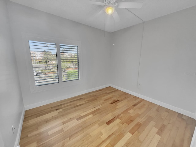 empty room with baseboards, a ceiling fan, and light wood finished floors