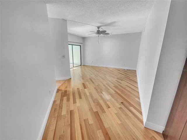 empty room featuring baseboards, a textured ceiling, ceiling fan, and light wood finished floors