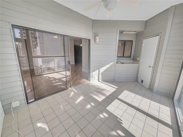 unfurnished bedroom with tile patterned flooring, wooden walls, and a ceiling fan