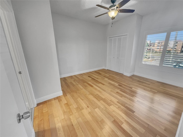 unfurnished bedroom with a closet, baseboards, a ceiling fan, and light wood finished floors