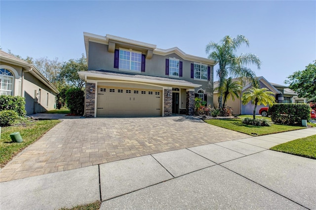 view of front of property with a front lawn, stucco siding, decorative driveway, stone siding, and an attached garage