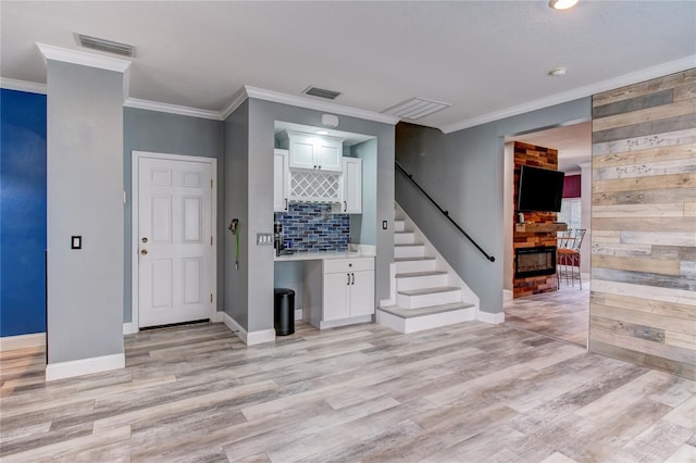 entryway featuring stairs, visible vents, light wood finished floors, and wood walls