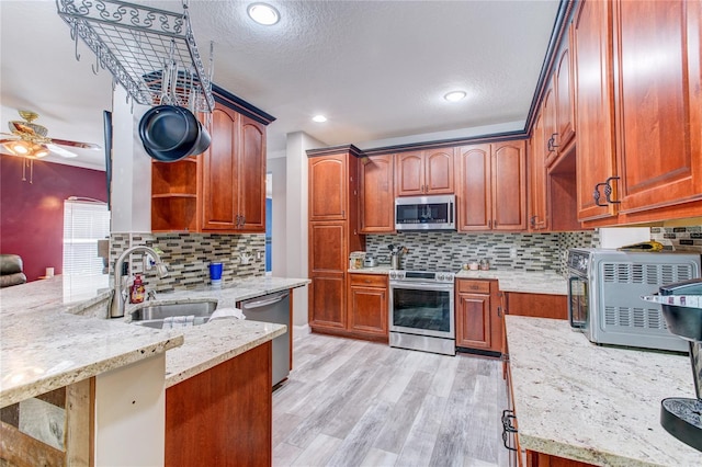 kitchen featuring a sink, open shelves, light stone counters, stainless steel appliances, and ceiling fan