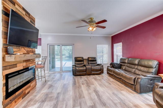 living room featuring wood finished floors, a glass covered fireplace, a ceiling fan, and ornamental molding