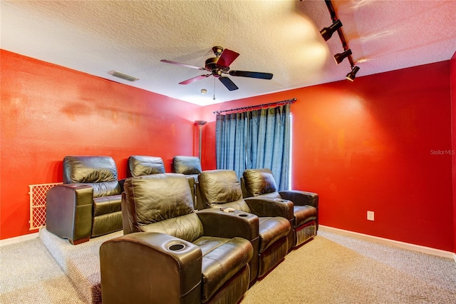 cinema room featuring a textured ceiling, carpet flooring, visible vents, and ceiling fan