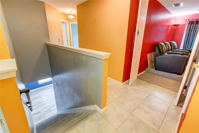 hallway featuring light tile patterned floors, visible vents, and baseboards