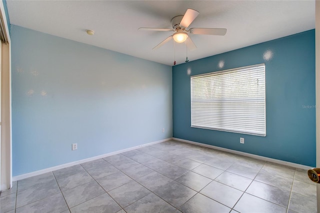 spare room featuring tile patterned floors, a ceiling fan, and baseboards