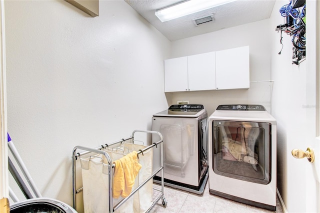 clothes washing area featuring light tile patterned floors, visible vents, cabinet space, a textured ceiling, and washer and clothes dryer