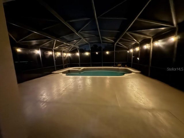 pool at night featuring an outdoor pool, a lanai, and a patio area