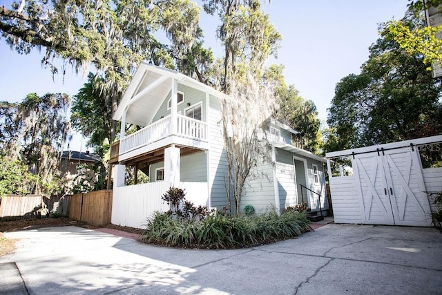 view of side of home featuring a balcony, a gate, and fence