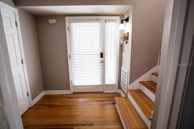 entryway featuring stairs, baseboards, and wood finished floors