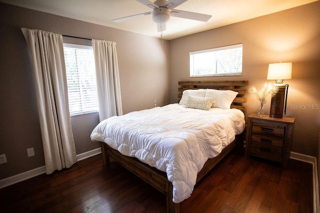 bedroom featuring a ceiling fan, multiple windows, baseboards, and dark wood-style flooring