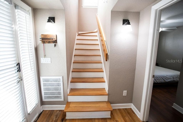 stairs featuring a ceiling fan, wood finished floors, visible vents, and baseboards