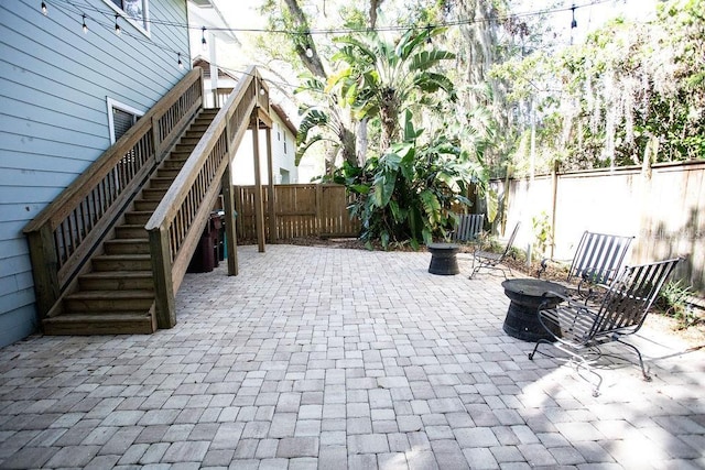 view of patio featuring a fire pit, a fenced backyard, and stairs