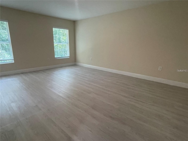 spare room featuring baseboards and wood finished floors