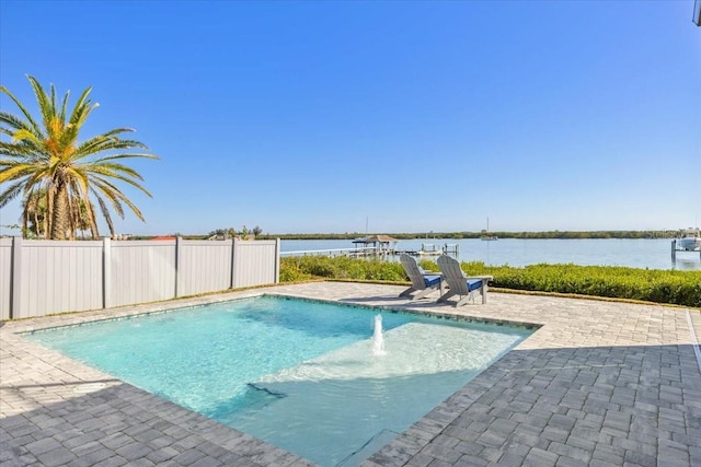 outdoor pool with a water view, fence, and a patio area