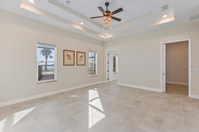 spare room featuring a raised ceiling, baseboards, visible vents, and ceiling fan