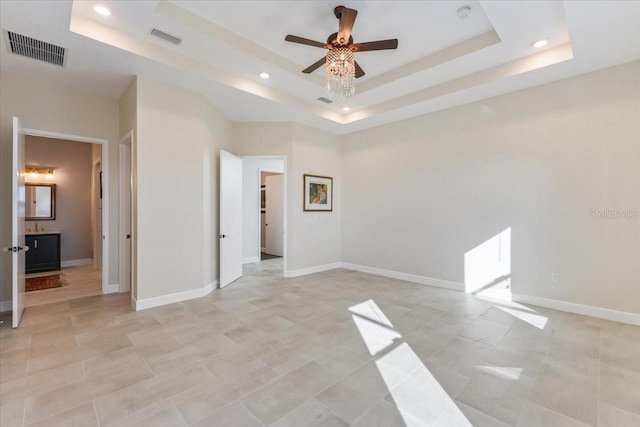 unfurnished room featuring a tray ceiling, visible vents, and ceiling fan