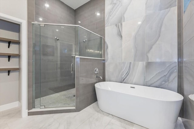 full bathroom featuring a stall shower, marble finish floor, and a freestanding bath