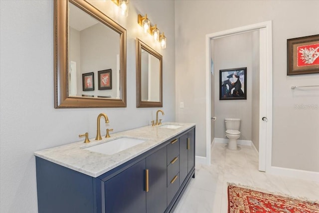 bathroom featuring a sink, baseboards, toilet, and double vanity