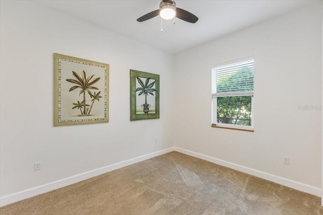 carpeted spare room featuring ceiling fan and baseboards