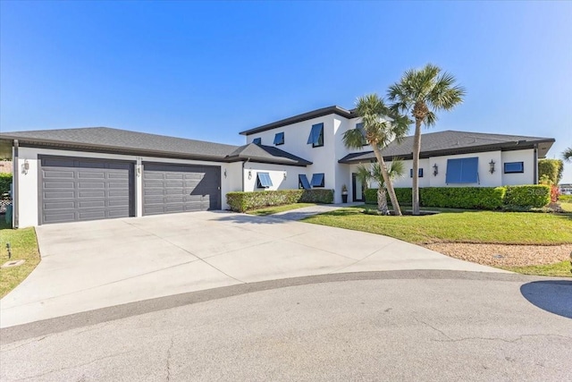 view of front of home featuring stucco siding, driveway, a front yard, and a garage