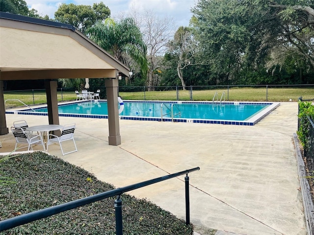 community pool with fence, a lawn, and a patio area