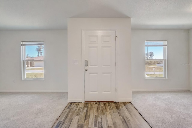 entrance foyer with carpet flooring, a textured ceiling, and baseboards