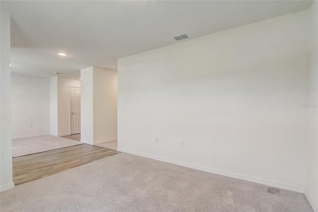 spare room with recessed lighting, carpet flooring, baseboards, and visible vents