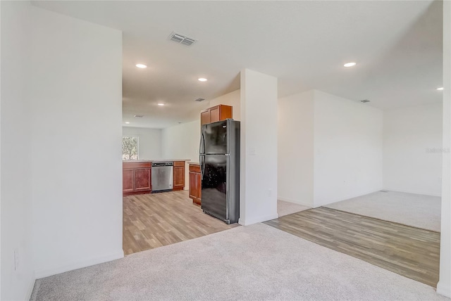 kitchen with stainless steel dishwasher, light colored carpet, visible vents, and freestanding refrigerator