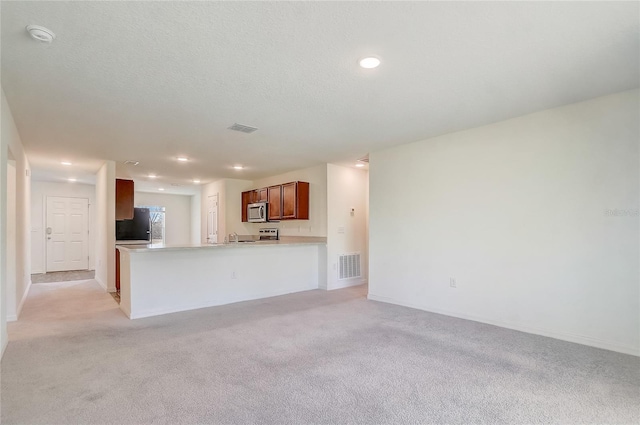 kitchen featuring stainless steel microwave, light carpet, refrigerator, and visible vents