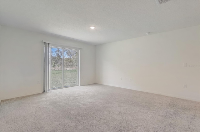 unfurnished room featuring visible vents, light carpet, and a textured ceiling