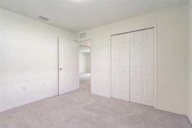 unfurnished bedroom with visible vents, baseboards, carpet, and a closet