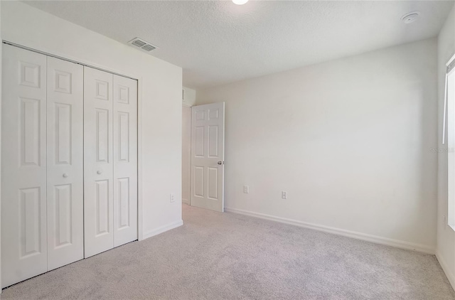 unfurnished bedroom with baseboards, visible vents, a closet, a textured ceiling, and carpet flooring