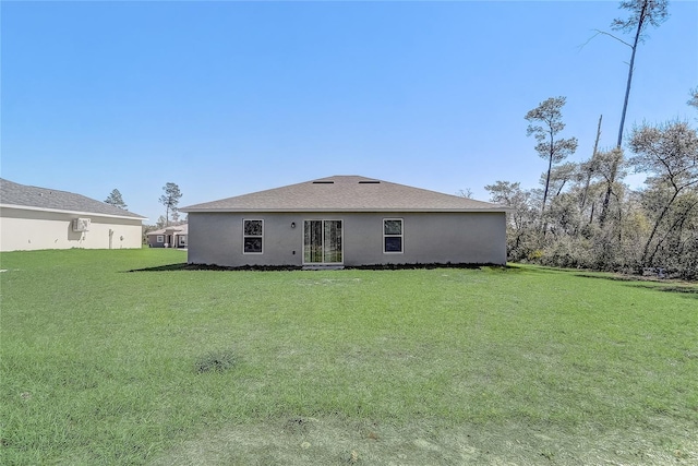 rear view of property with stucco siding and a lawn