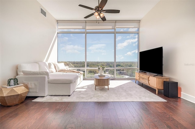 living area with visible vents, baseboards, ceiling fan, a wall of windows, and wood finished floors