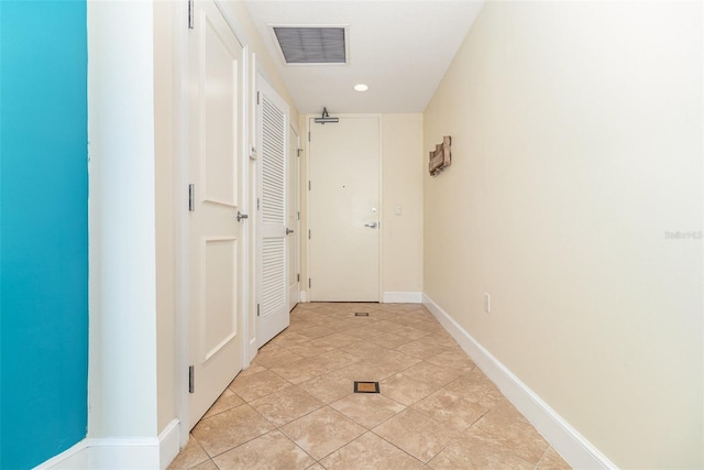 hallway with light tile patterned floors, baseboards, and visible vents