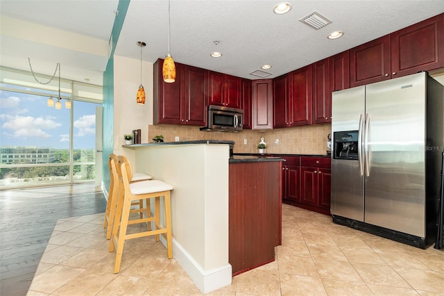 kitchen featuring visible vents, backsplash, dark countertops, stainless steel appliances, and reddish brown cabinets