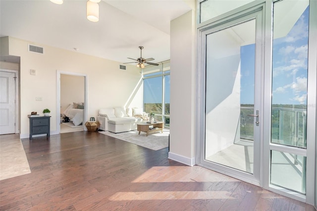 living area featuring a wealth of natural light, visible vents, wood finished floors, and ceiling fan