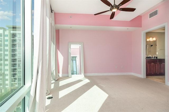 spare room with light carpet, visible vents, ceiling fan, and baseboards