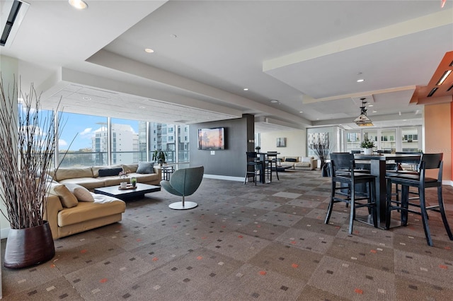 carpeted living area with recessed lighting, baseboards, a raised ceiling, and a city view