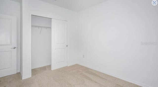 unfurnished bedroom featuring a closet and light colored carpet