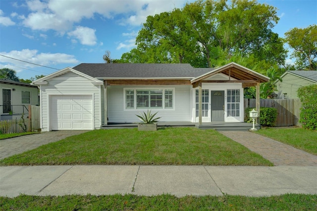 ranch-style home featuring decorative driveway, fence, roof with shingles, a front yard, and a garage