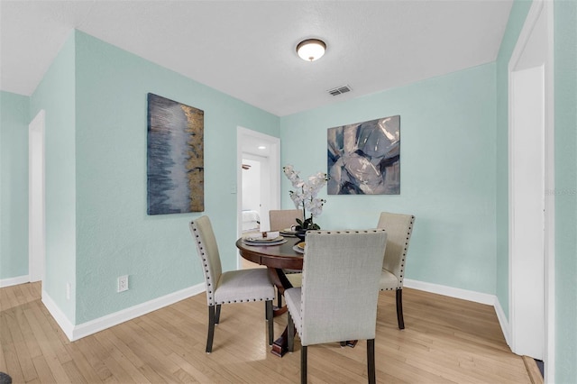 dining area with visible vents, baseboards, and wood finished floors