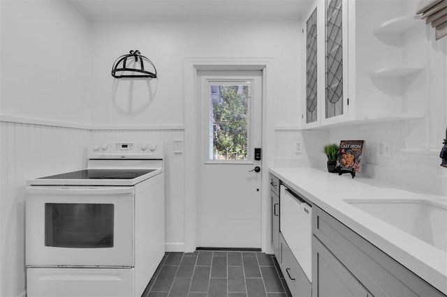 kitchen with a sink, open shelves, white appliances, wainscoting, and light countertops