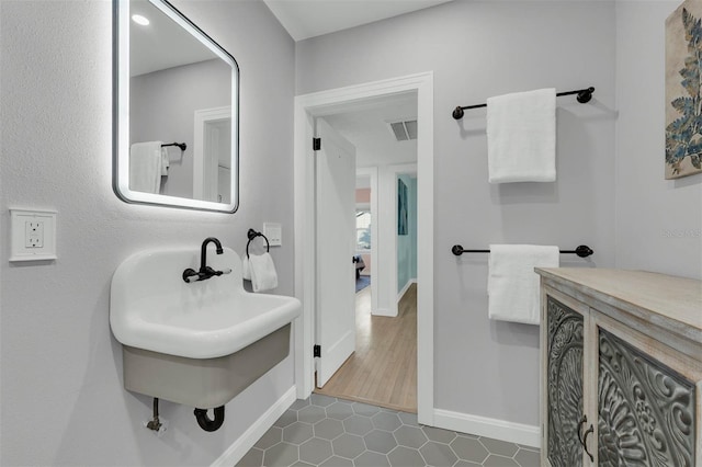 bathroom featuring tile patterned floors, baseboards, visible vents, and a sink