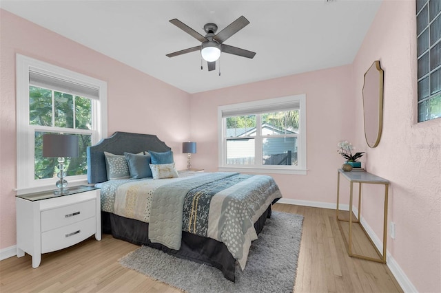 bedroom featuring multiple windows, baseboards, and light wood finished floors